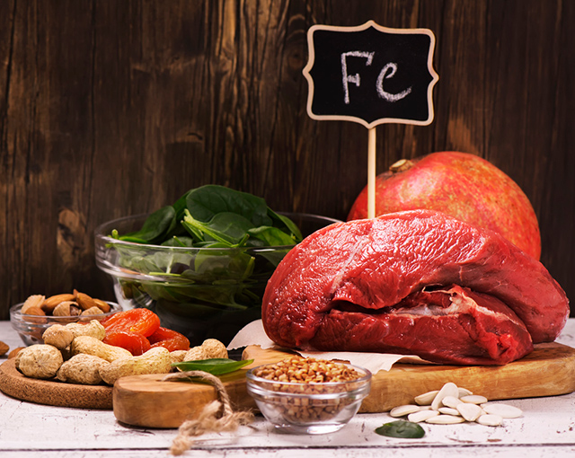Variedade de produtos saudáveis ricos de ferro, tais como carne, frutos secos e espinafres.