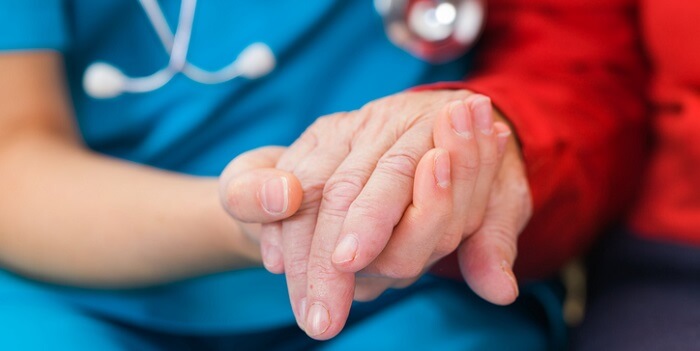 Duas mãos unidas simbolizam a dualidade da vida: uma reflete a fragilidade da doença de Parkinson, a outra representa vitalidade e apoio.
