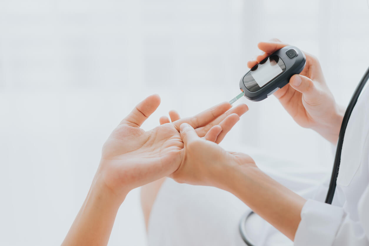 Médico a utilizar um glicosímetro para medir os níveis de glicose no sangue de um paciente.