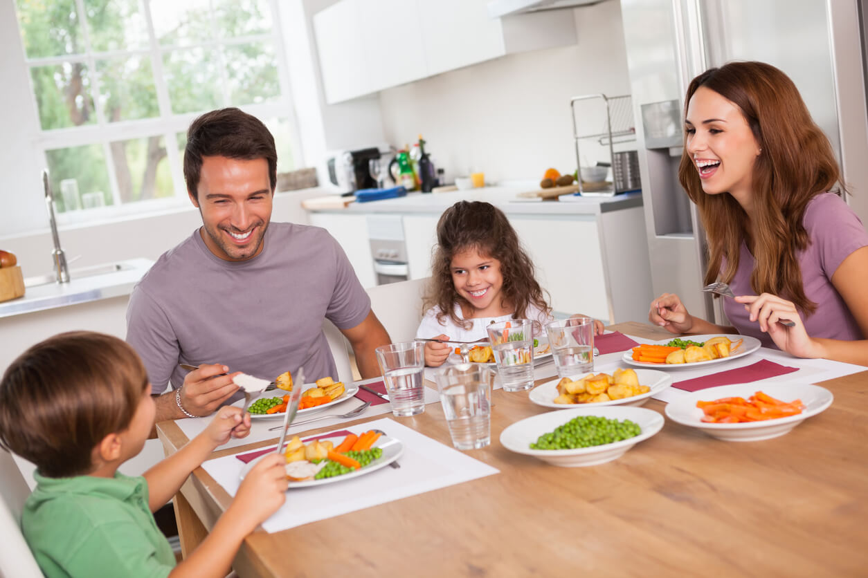 Família feliz a partilhar uma refeição saudável em casa, fortalecendo a saúde do coração e rins, enquanto reforça a harmonia e união familiar.