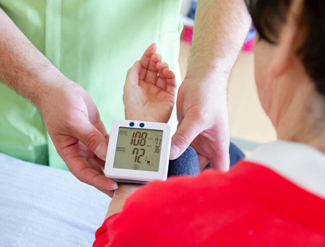 Profissional de saúde a medir a pressão arterial de uma paciente com um dispositivo digital.