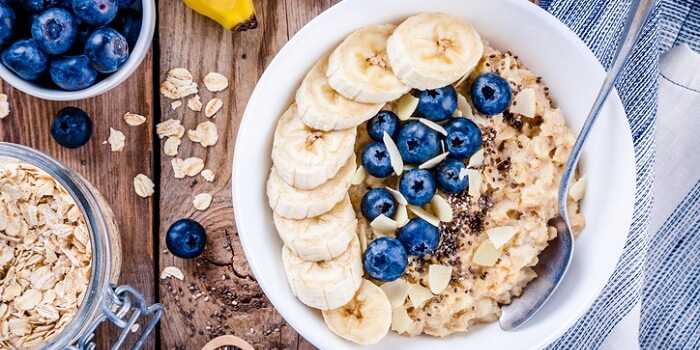 Tigela de aveia com banana, mirtilos e amêndoas fatiadas, um pequeno-almoço saudável e equilibrado, ideal para a saúde do coração.