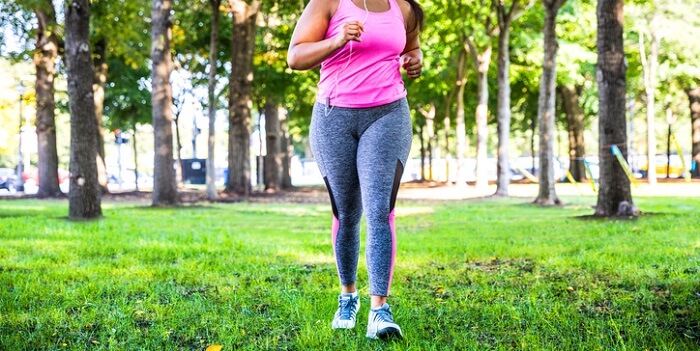 Uma mulher a correr num parque, que simboliza a importância da atividade física para manter a saúde cardiovascular.