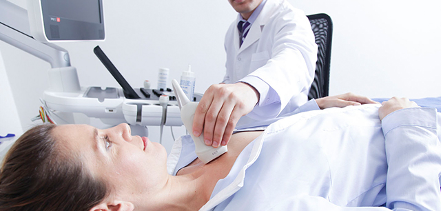 Médico a realizar o eco doppler a um paciente feminino, dentro do seu consultório para prevenir o AVC: aterosclerose das artérias.