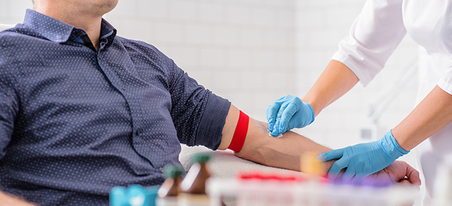 Profissional de saúde a estancar o sangue a um paciente depois de tirar sangue para análises. Procedimento normal de um check-up.
