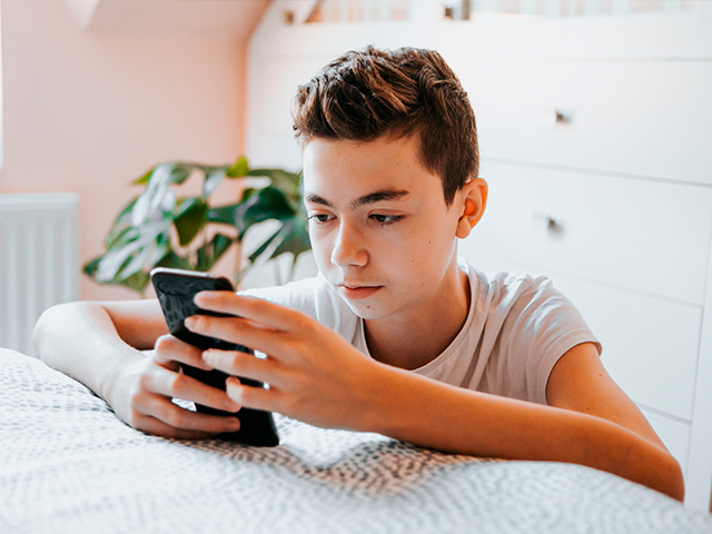 Jovem a usar o telemóvel, representação do impacto das redes sociais na saúde mental dos jovens.