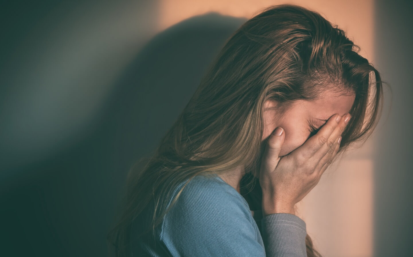 Mulher sozinha, triste em casa. Monstra a importância do Dia Mundial da Saúde Mental.