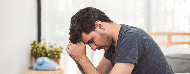 Mulher deitada numa cama, a olhar para o teto, símbolo dos efeitos introspetivos e isolantes das depressões minor.