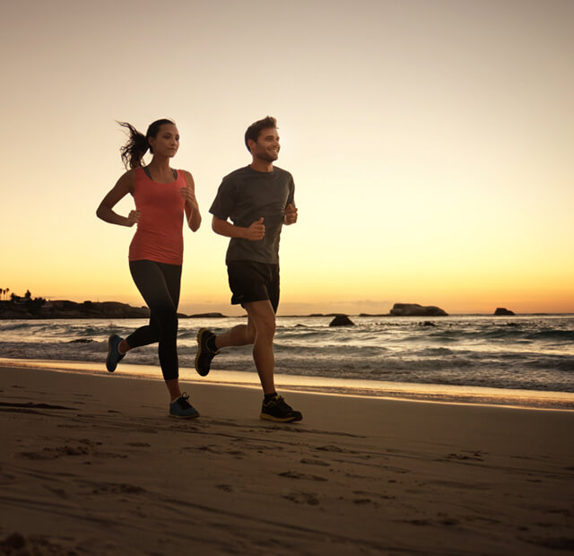 Casal ao correr à beira-mar, ao fim do dia.