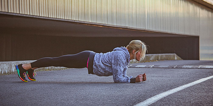 Mulher a fazer uma prancha ao ar livre. Um exercício útil para alcançar uma barriga lisa.