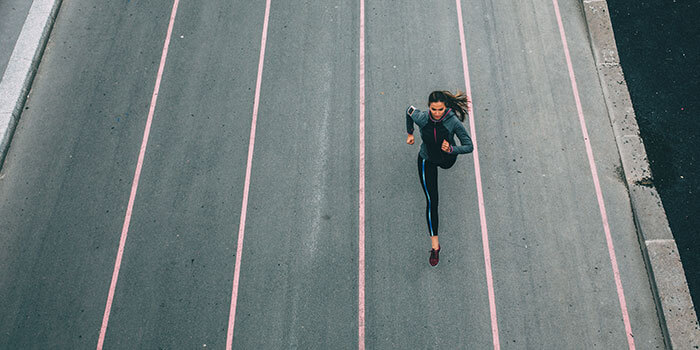 Mulher a correr na rua. Um exercício que mobiliza todo o corpo, tendo assim mais probabilidades de resultar numa barriga lisa.