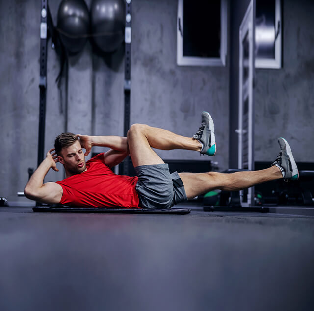 Homem no ginásio a fazer abdominais, um tipo de exercício também útil para se fazer em casa.