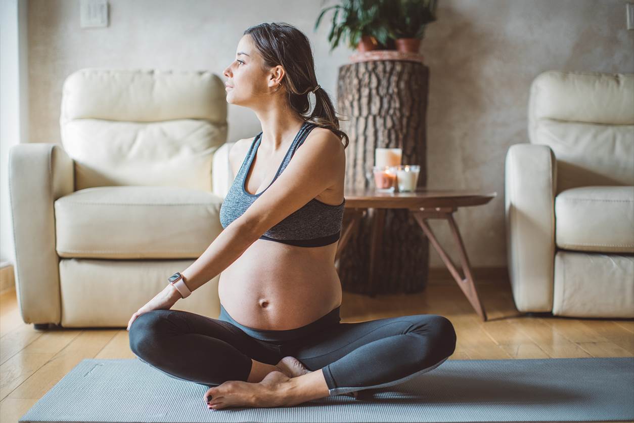jovem mulher gravida pratica pilates em casa para aproveitar os benefícios desta atividade no período de gestação