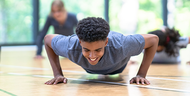 adolescente faz flexões, uma prática de exercício físico que ajuda a gastar calorias