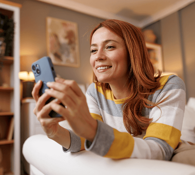 Senhora a olhar para telemóvel no sofá, enquanto utiliza a app Médis Active